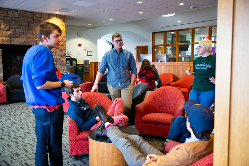Students sit on comfy chairs near a fireplace in a popular study spot on campus.