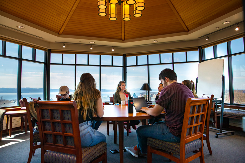Students work in one of the top study spots on campus: A room with large windows overlooking the lake and mountains.