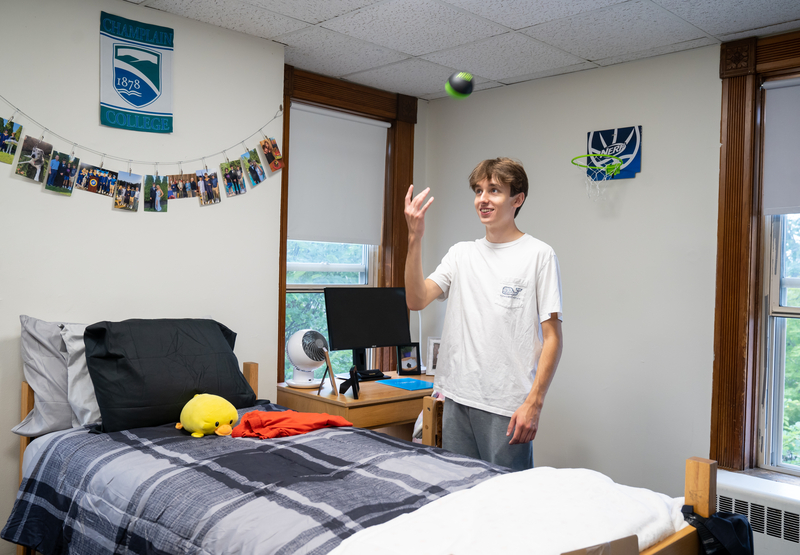 A student throws a NERF basketball into a net on the wall.