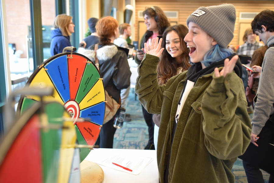 A student throws their hands up in the air after spinning a colorful wheel.