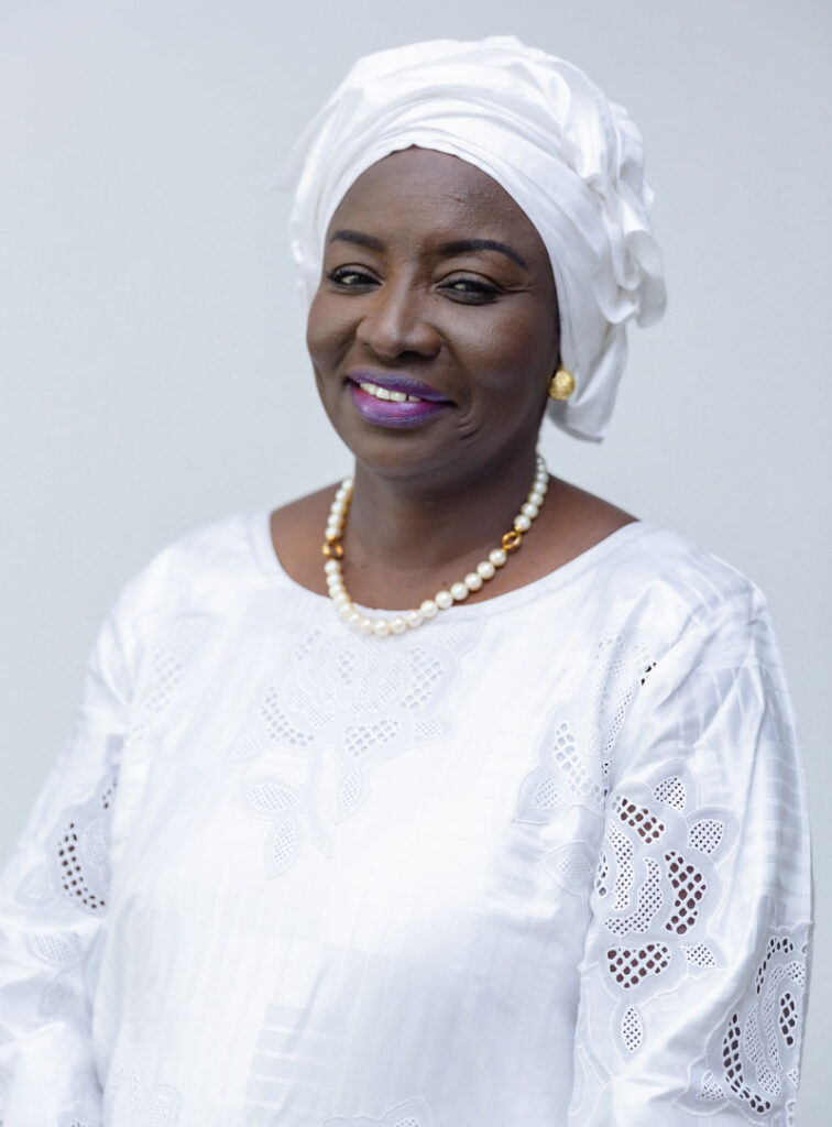 Headshot of Dr. Aminata Touré wearing a white blouse, white pearl necklace, and a white head wrap