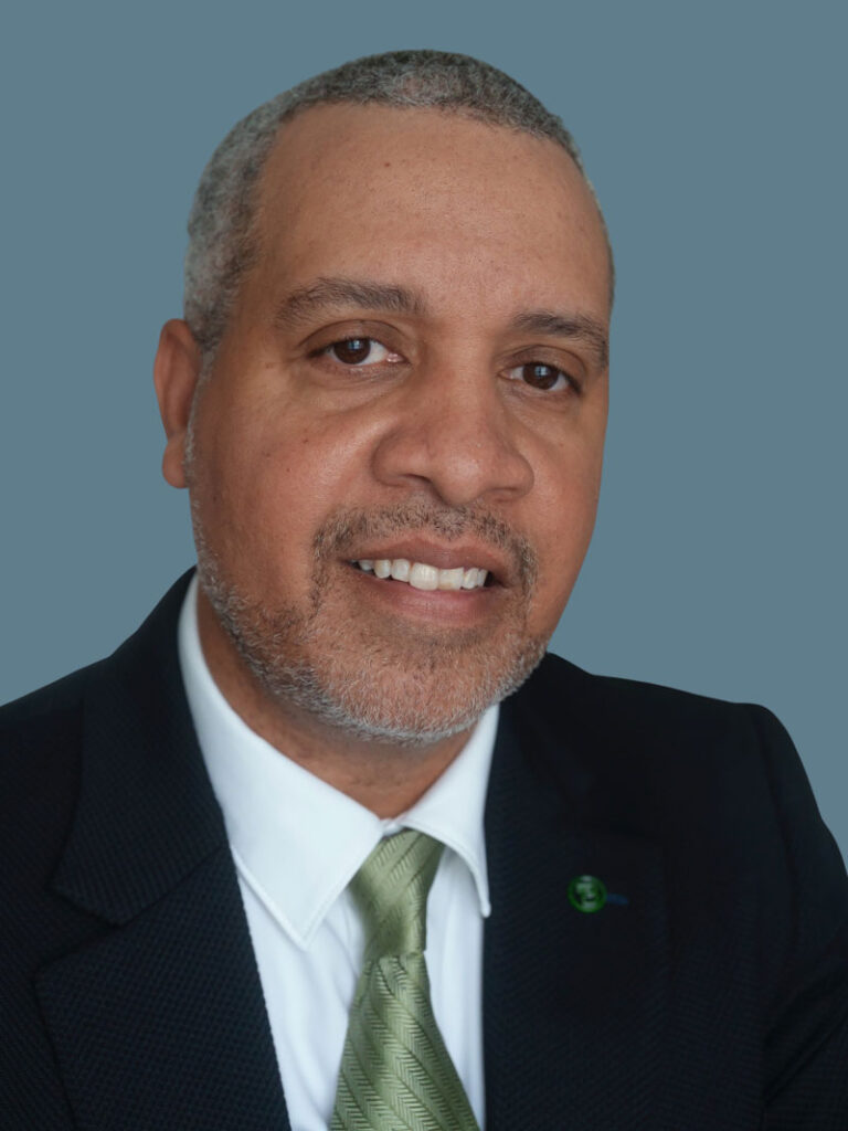 Headshot of Dr. Craig Winstead smiling wearing a black suit jacket, green tie, and white shirt