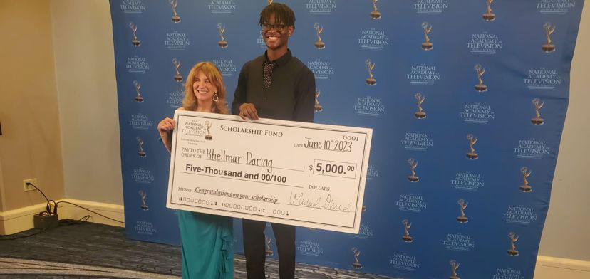 Khellmar Daring accepts an oversized check for five thousand dollars from a presenter at the National Academy of Television Arts and Sciences.