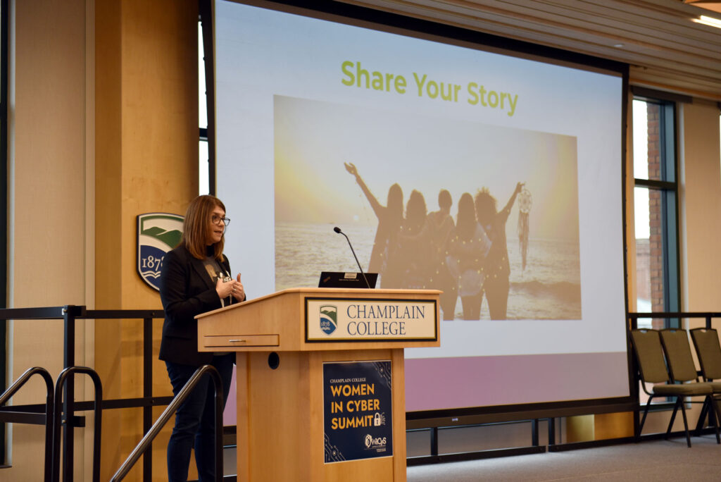 Michele Tomasic speaks at a podium at Champlain College's Women in Cyber Summit
